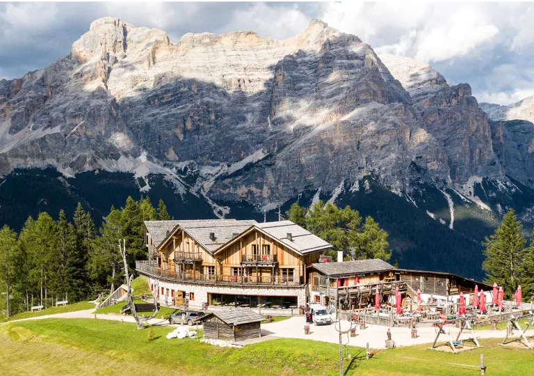 Outdoor view of hotel lodge with red umbrellas outside, with a large mountain in the background