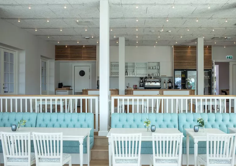 Kitchen with an espresso machine and turquoise blue couches and white chairs