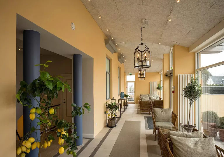 Hallway with tables and chairs and a lemon tree between two blue pillars