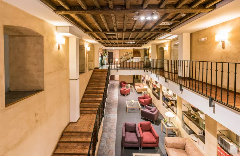 Indoor library with cushioned chairs and a stairway on the left