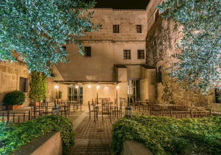 Outdoor dining area surrounded by trees and tall stone buildings