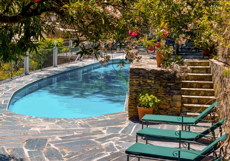 Outdoor pool area with stone walkways and green pool chairs