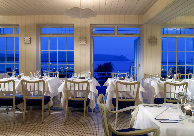 Indoor dining hall with open doors looking out to the ocean