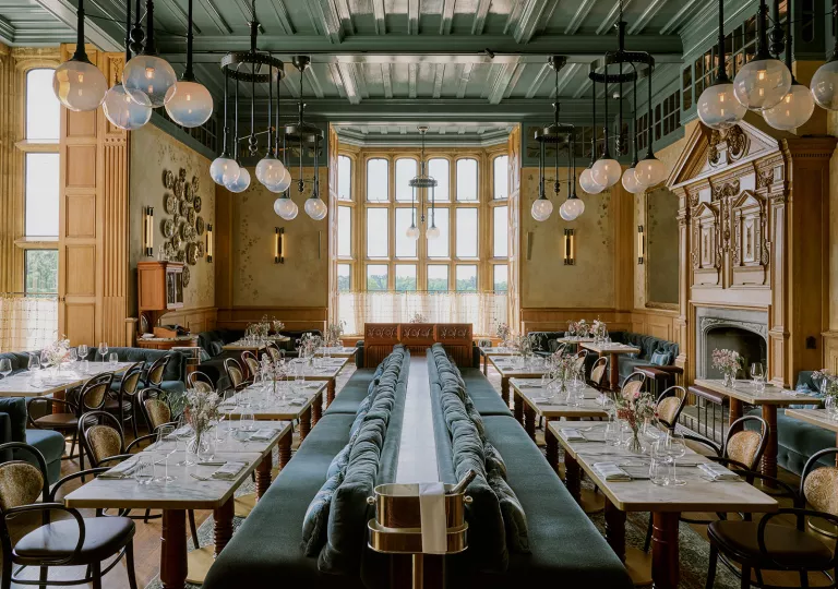 Indoor dining area with green couches in the center and vases on each table