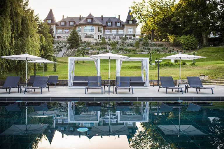 Outdoor pool with umbrellas with a castle-like building in the background