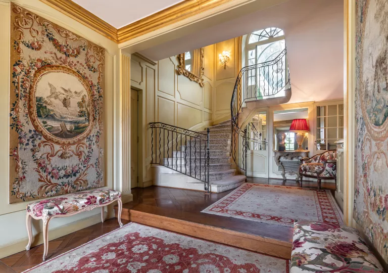 Indoor foyer with a tall staircase and large rugs on the ground