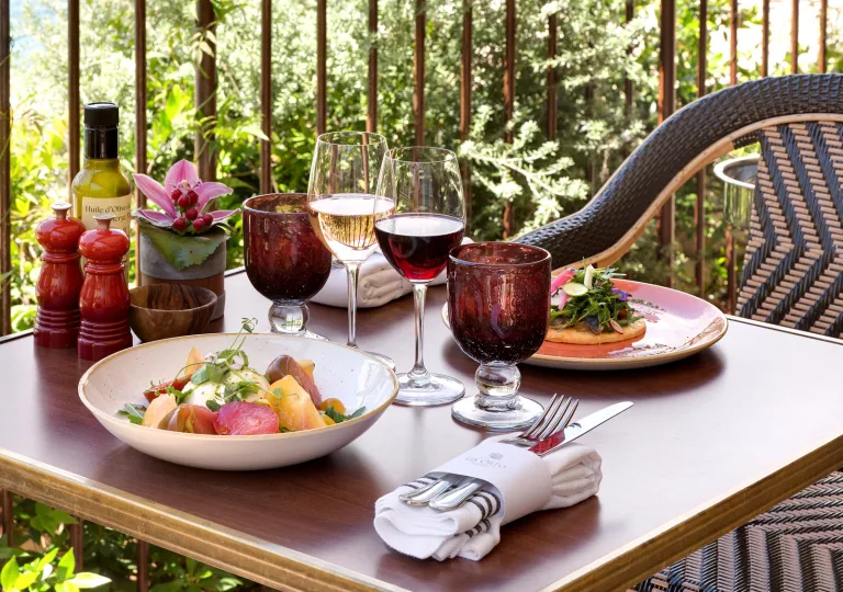 Dining table outdoors with plates of food and full glasses of wine