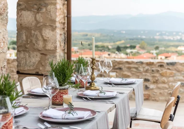 Outdoor dining table with wine glasses, overlooking a small town