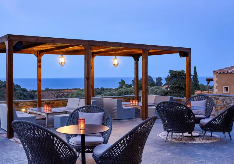 Outdoor lounge area with cushioned seats and wooden pillars