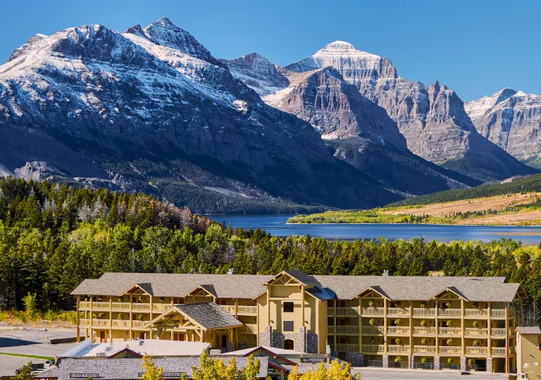 Long yellow hotel building with tall mountains in the background
