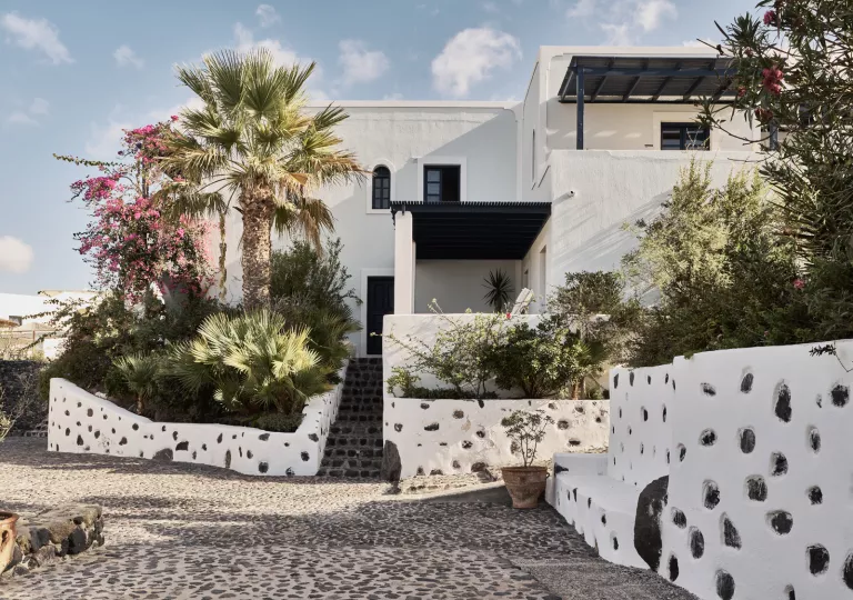 Exterior view of a white building with black accents, with a stone pathway