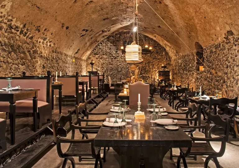 Indoor dining area with large, stone walls and light fixtures hanging from the ceilings