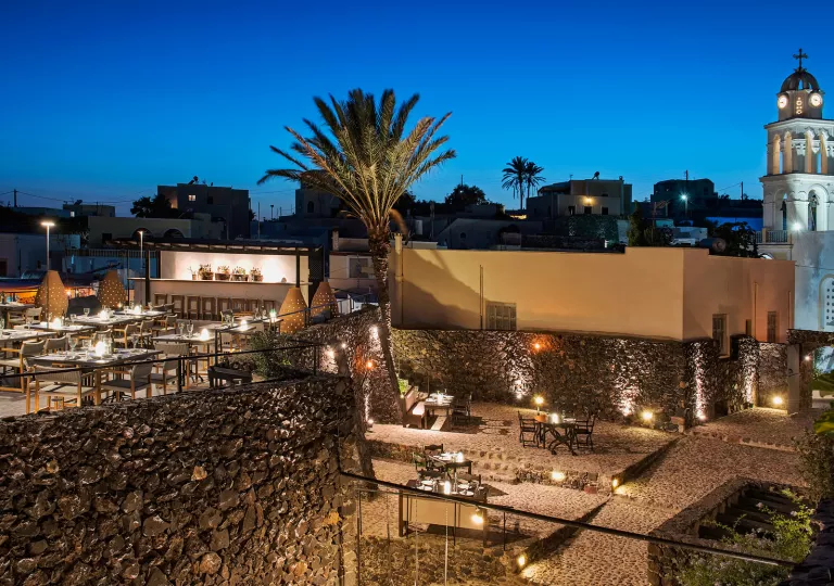 Sky view of illuminated outdoor patios with a rectangular building to the right