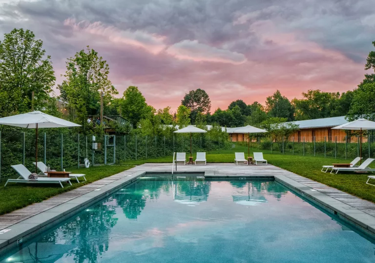 Outdoor pool surrounded by umbrellas and pool chairs