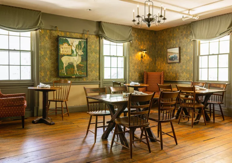 Indoor dining area with wooden tables and chairs, with large art pieces on the wall