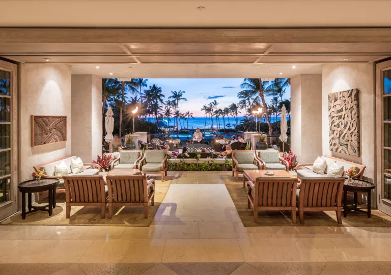 Lobby with a man playing a guitar in the background and the ocean behind him
