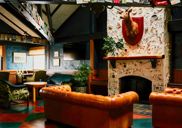 Indoor lounge area with orange and green couches surrounding a stone fireplace
