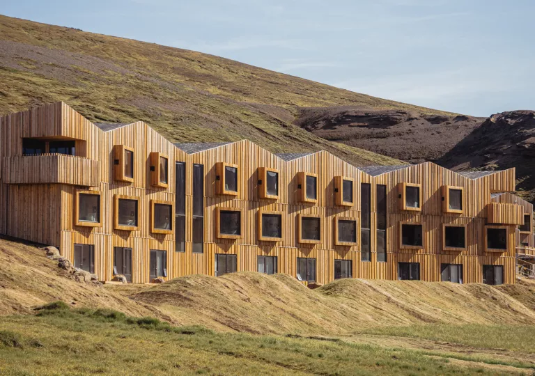 Hotel building made of wooden panels, with large open windows