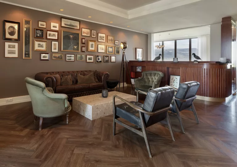 Lounge and seating area with leather chairs and sofas, and paintings on the wall