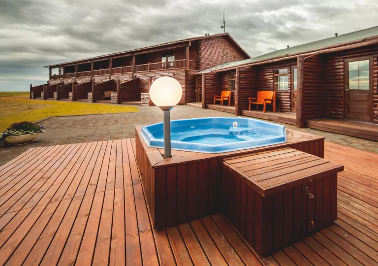 Outdoor hot tub on a wooden platform, next to a lodge building