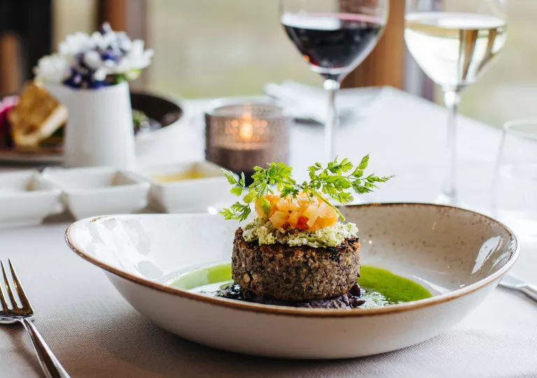 Plate with a small piece of steak in the center, on a table with a  tablecloth