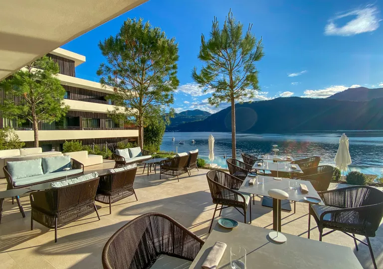 Outdoor lounge with dining tables, looking out to a large lake