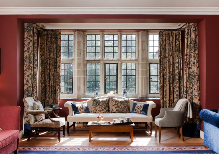 Sitting area with cushioned chairs and square pillows in front of large windows