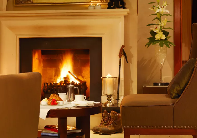 Leather couch in front of a white fireplace, with pastries and fruit on a circular coffee table