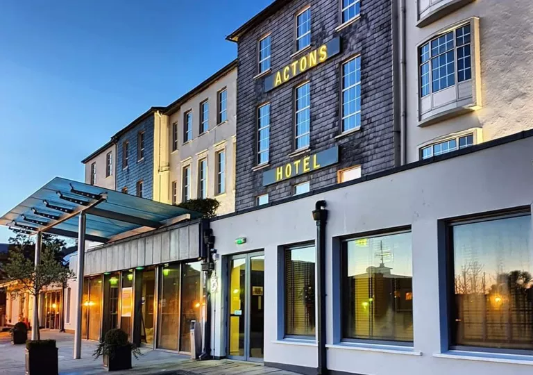 Exterior view of stone hotel building with large windows along the walls