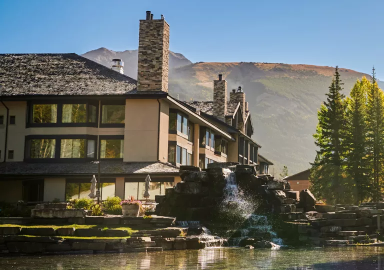 Outdoor view of a hotel with open windows and a stone fountain