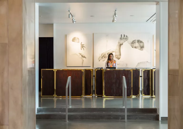 Woman standing at a reception table in front of a large hallway and small staircase