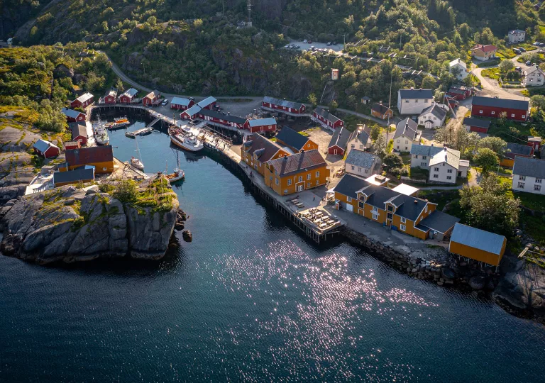 Sky view of orange and red buildings next to a cliff and a body of water