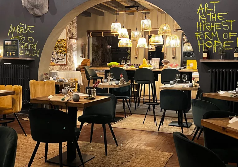 Indoor dining area with a large archway, and brown and black tables scattered across the room