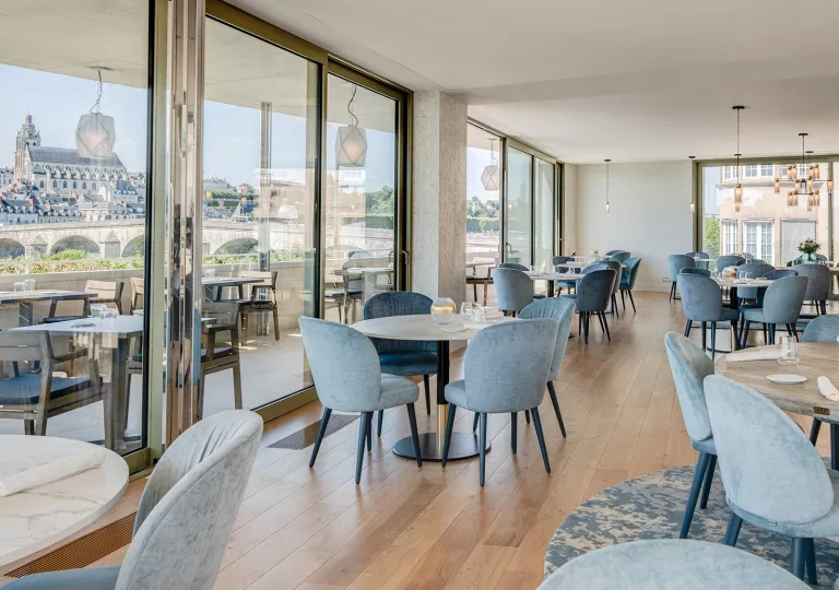 Indoor dining area with wooden tables and gray, cushioned chairs