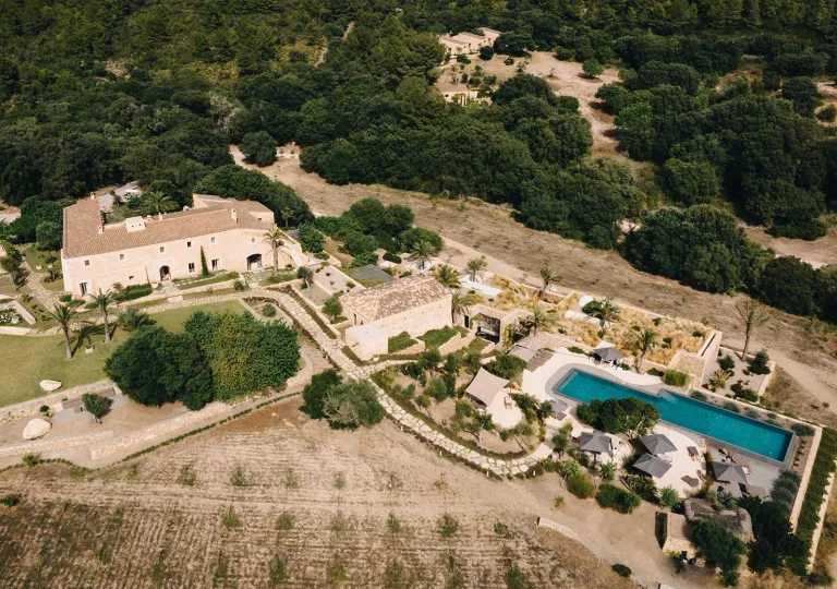 Top view of large white buildings and an outdoor pool surrounded by trees