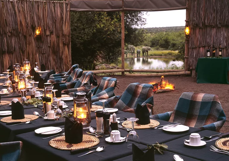Outdoor dining area with tables and chairs with a quilted blanket over each chair