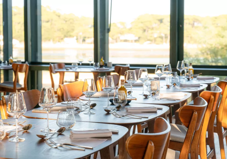 Long dining table with wooden chairs and wine glasses on either side