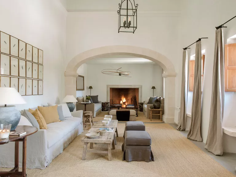 Indoor lobby with cushioned couches, long curtains and a fireplace in the back