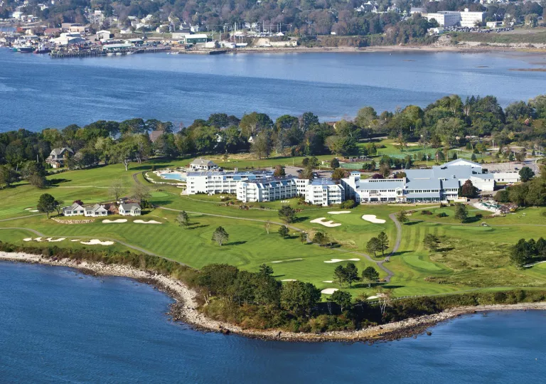Sky view of large white buildings in the middle of a grass field on a peninsula
