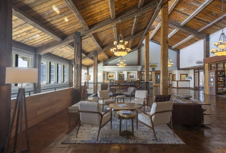 Indoor cabin lobby, with wooden pillars and tan chairs around a coffee table