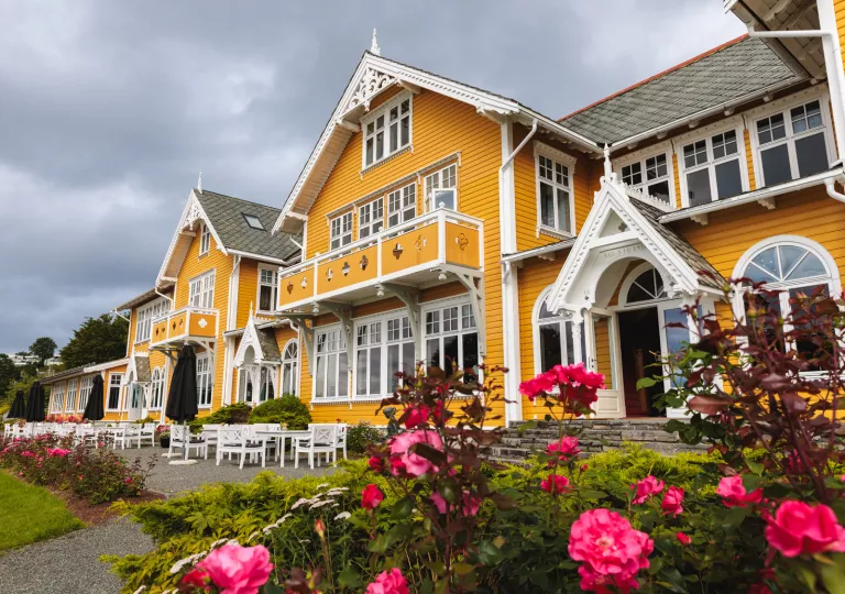 large yellow house flanked by rose bushes