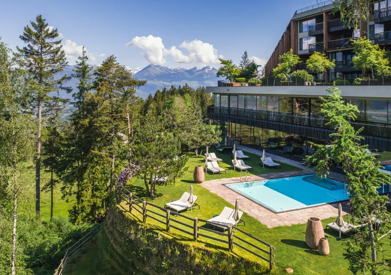 Outdoor view of hotel's outdoor pool, surrounded by umbrellas and pool chairs