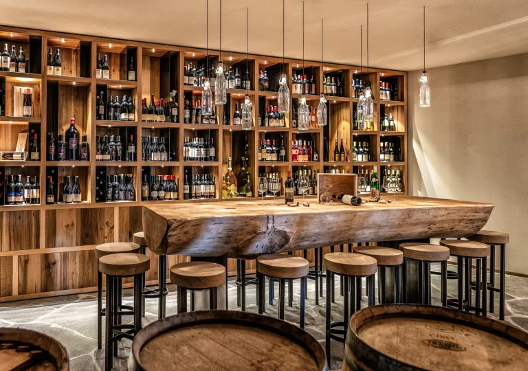 Wine cabinet behind a large table and stools made of tree stumps