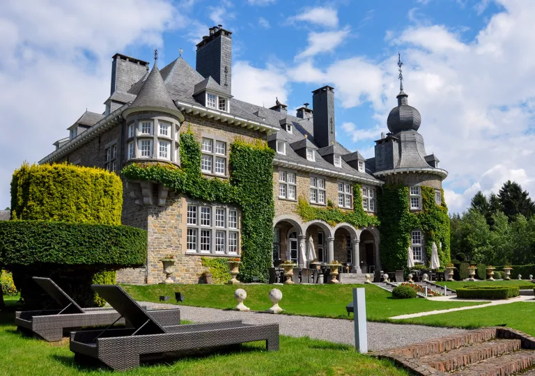 Stone building with trimmed hedges and gravel pathways