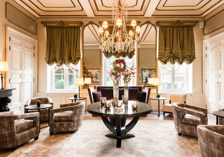 Indoor lounge with cushioned chairs and a large, crystal chandelier on the ceiling
