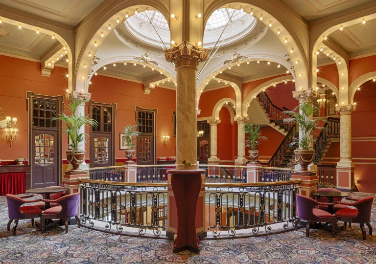 Upper floor lobby with tables, chairs and a staircase