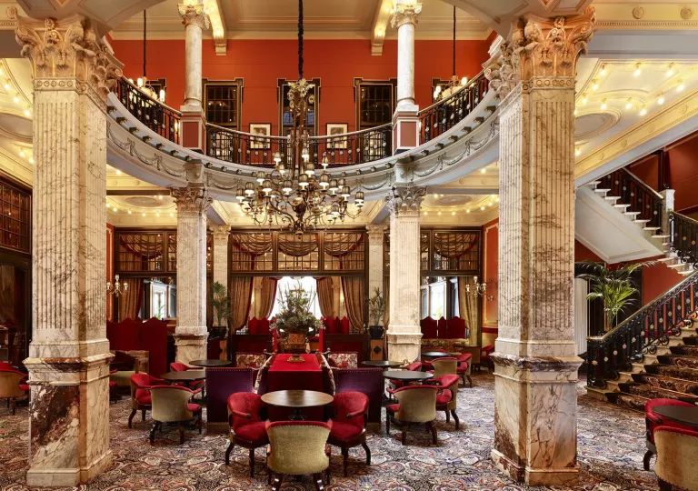 Dining room with chandelier, stone pillars and a staircase on the right