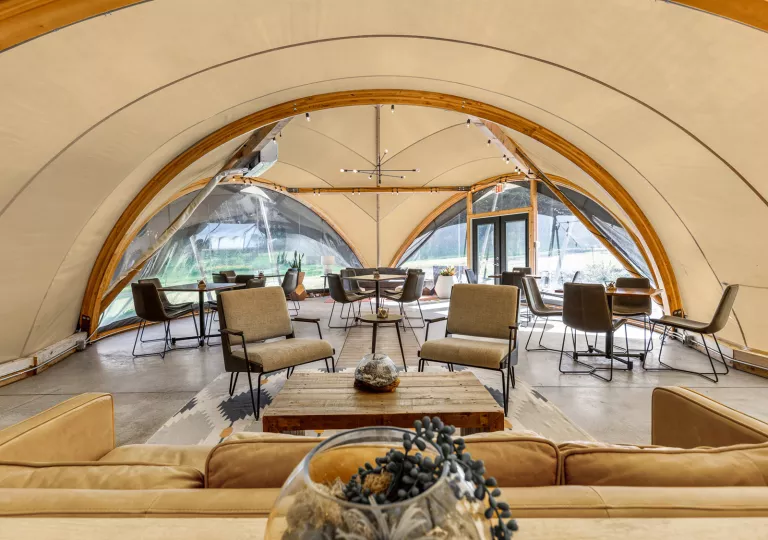 Indoor view of white hut, with a large sofa, chairs and dining tables