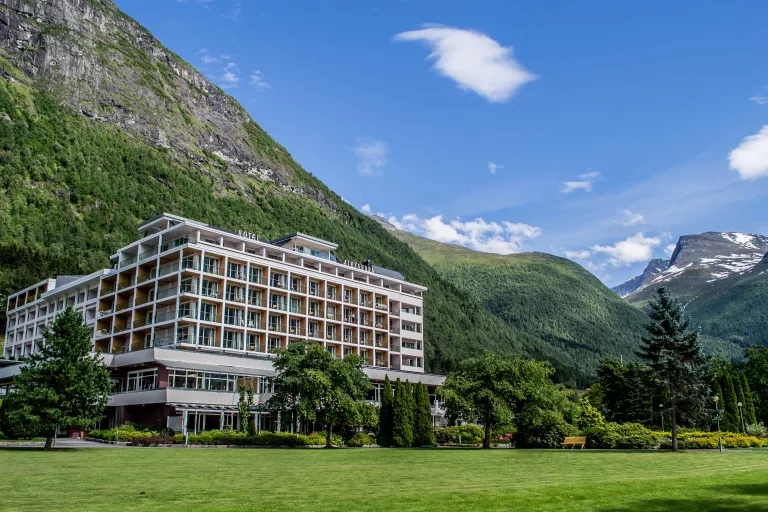 Large hotel surrounded by trees and tall mountains