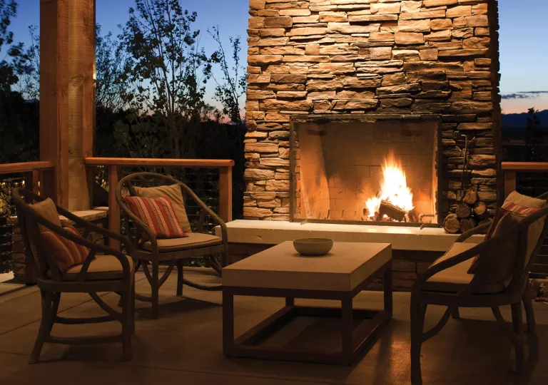 Four chairs in an outdoor patio in front of a stone fire place